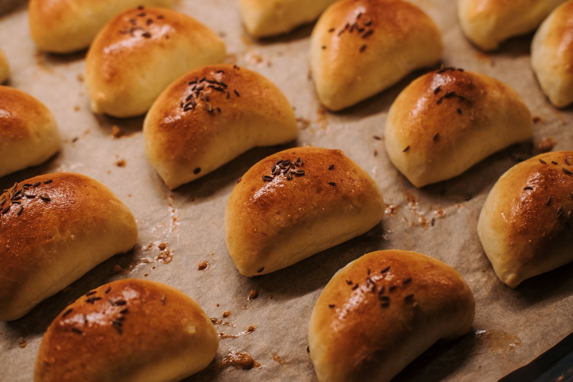 Soft golden potato dinner rolls on a baking sheet