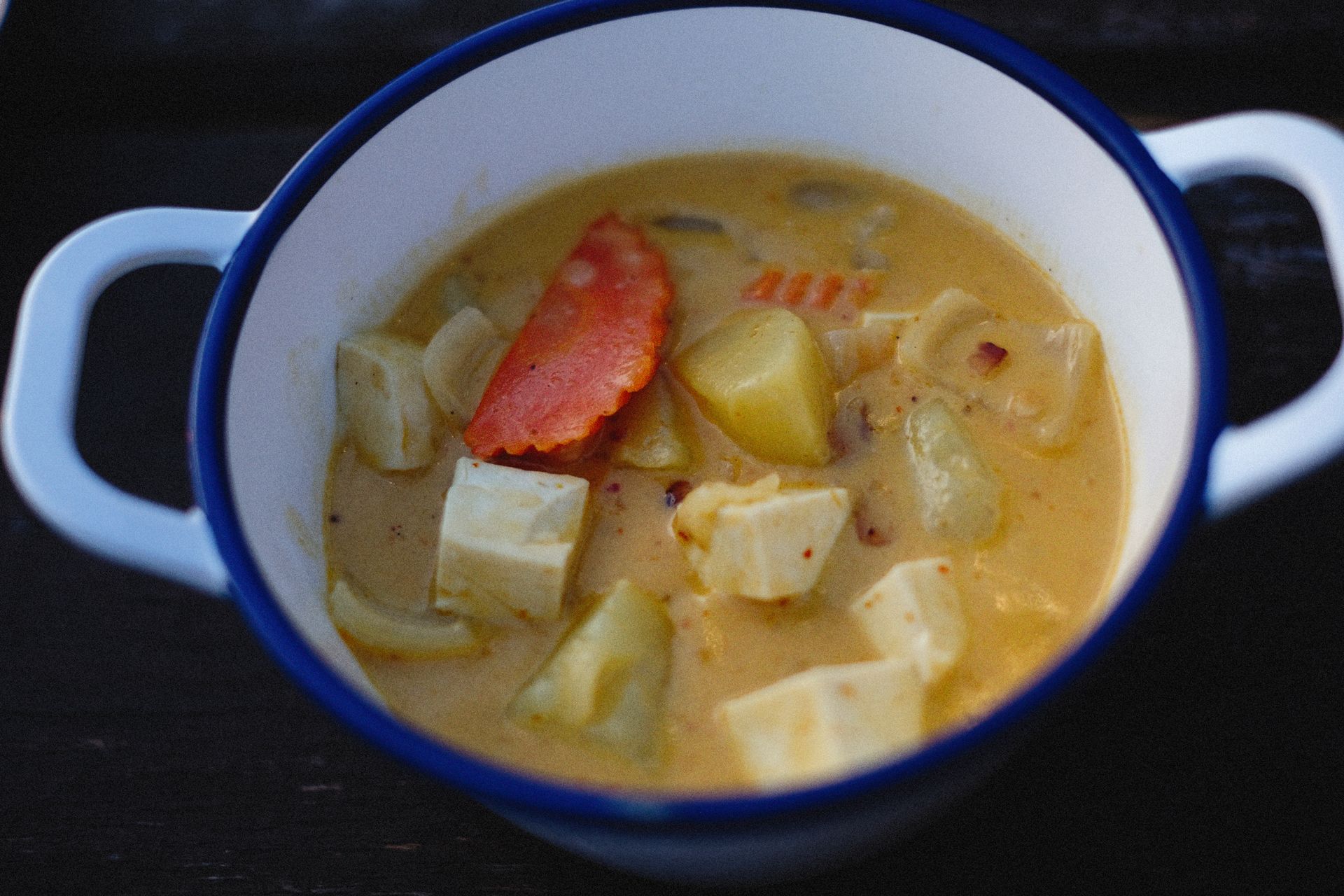 Creamy potato soup with sausage in a white pot
