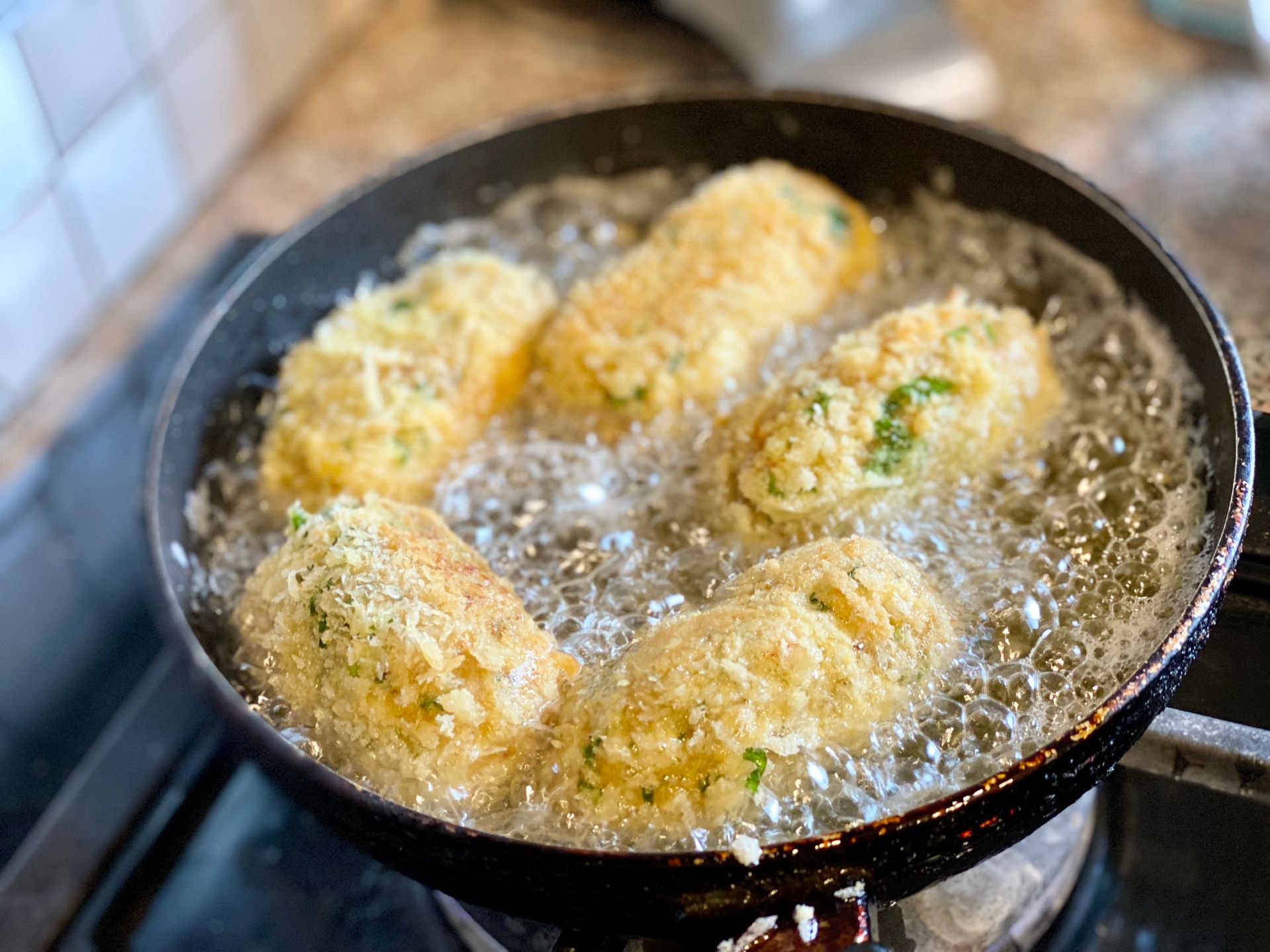 Panko-coated croquettes frying until golden in a pan of hot oil
