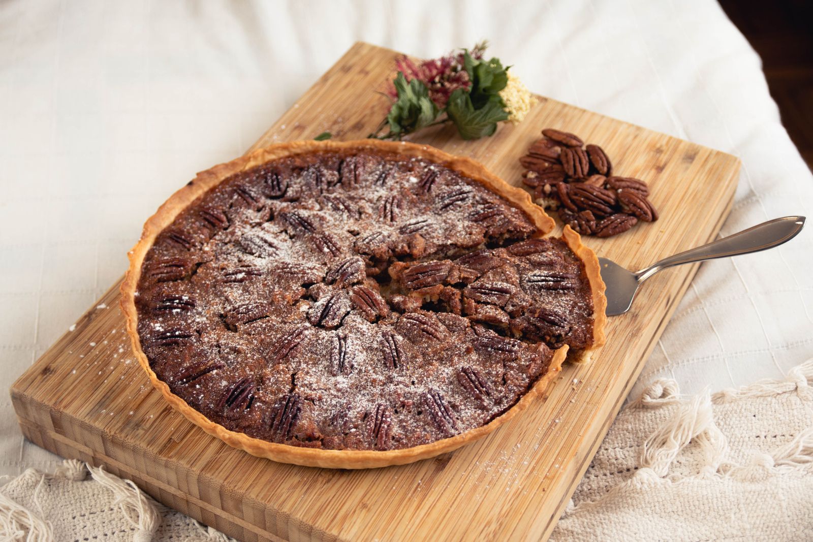 Homemade pecan pie on a wooden board with a few pecans