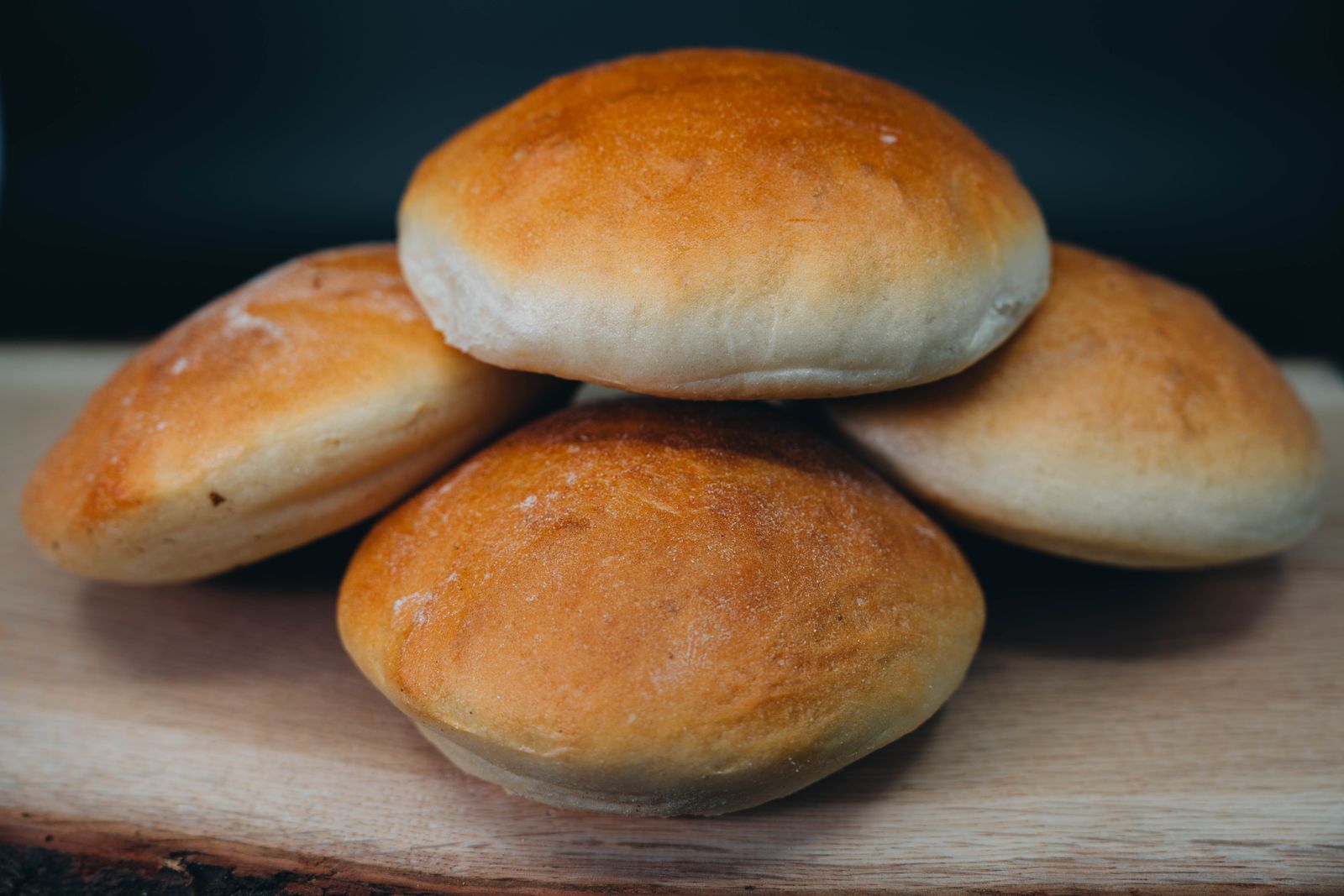 Golden brown dinner rolls stacked on a wooden board