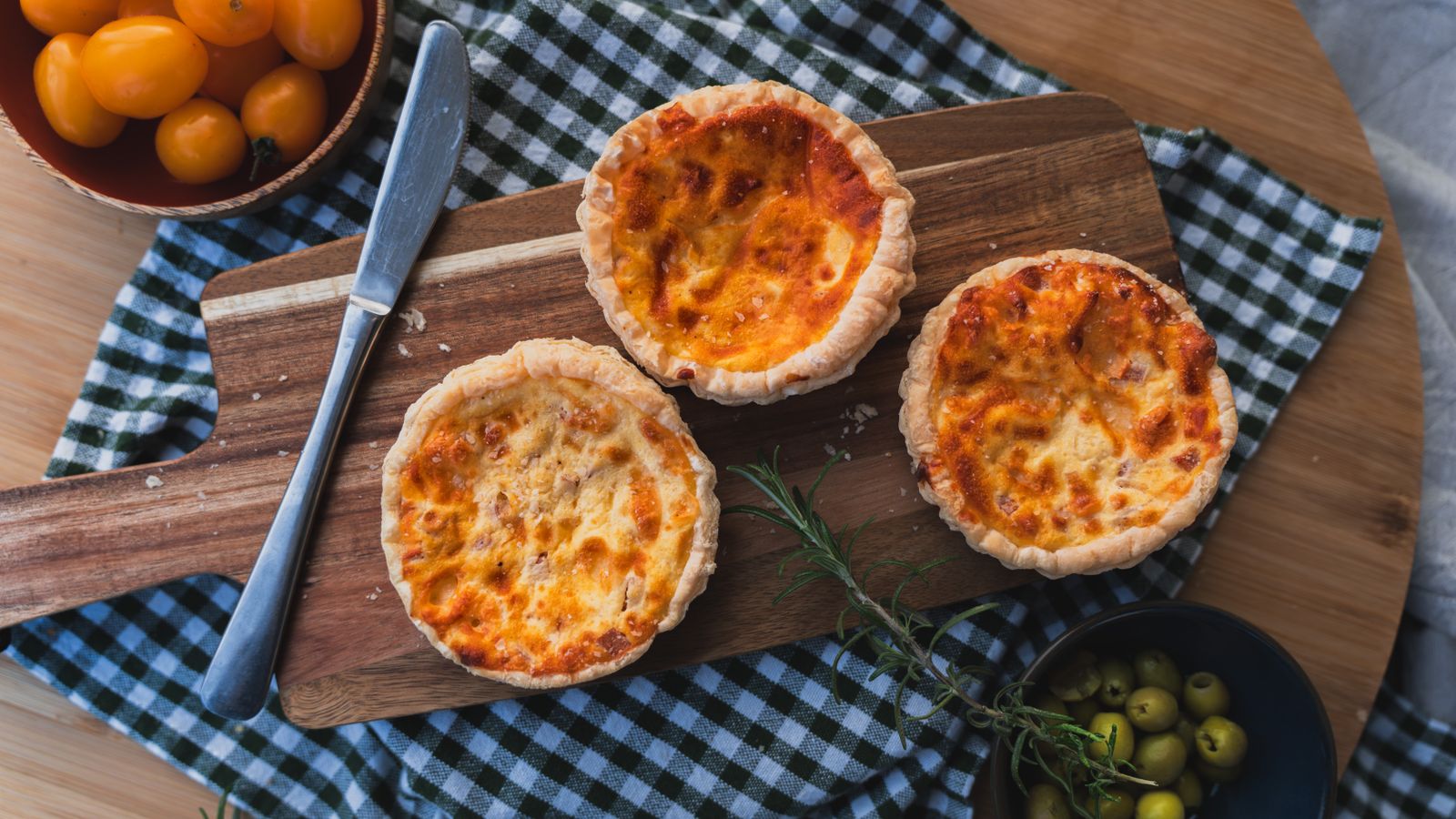 Three mini quiches on a cutting board with garnish