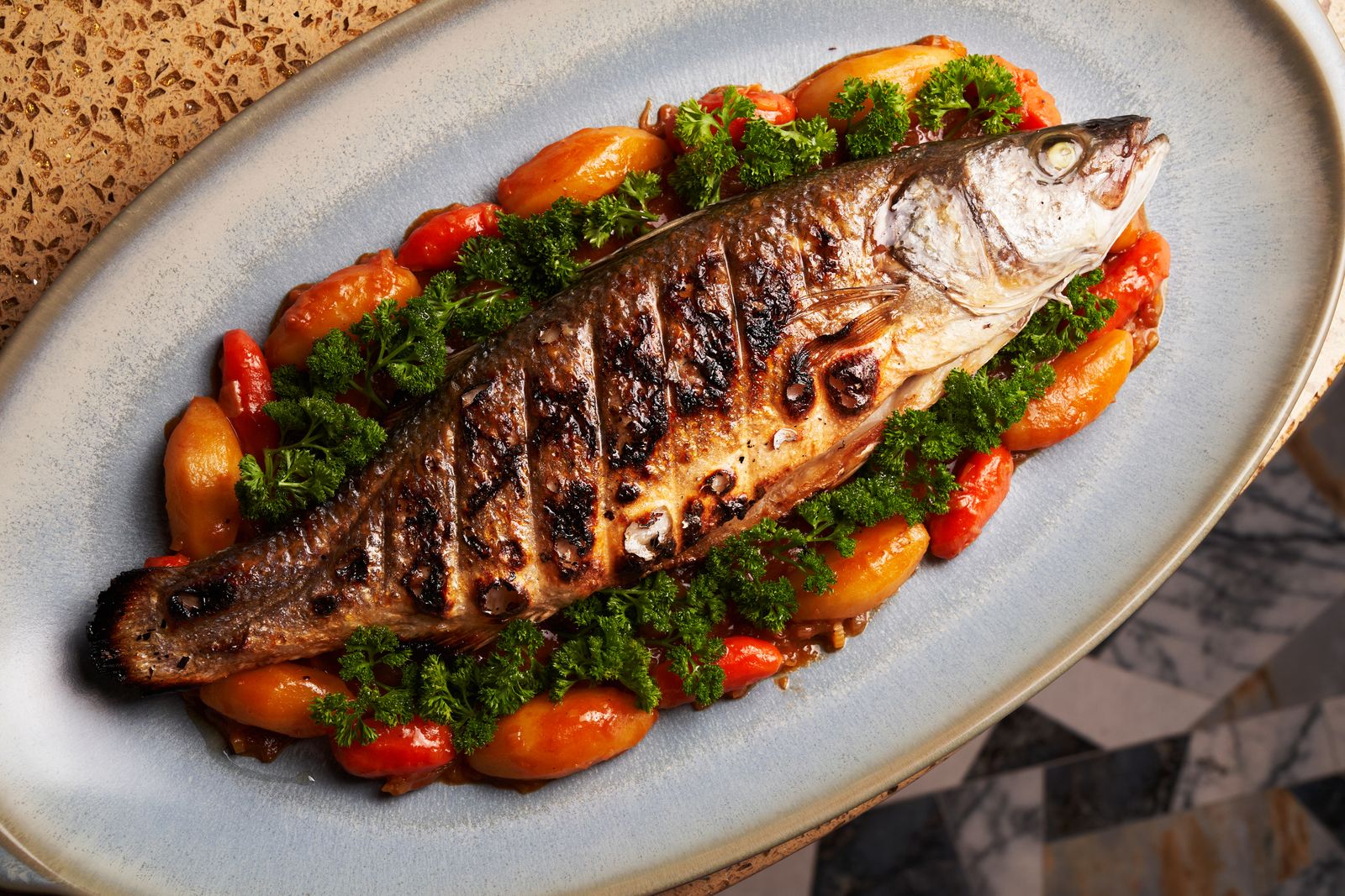 Feast of the Seven Fishes whole roasted fish with tomatoes and parsley on a platter