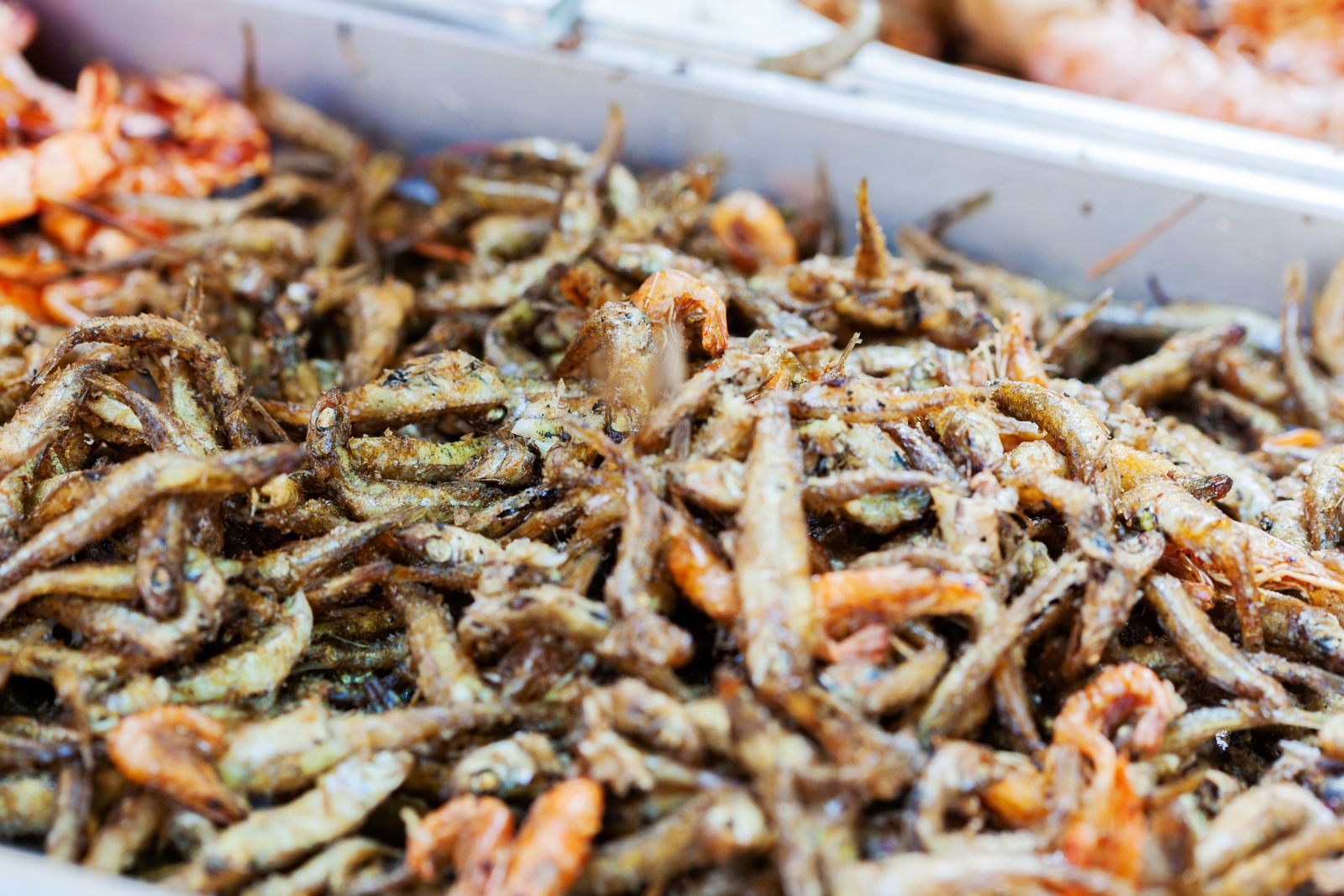 Crispy fried small fish and prawns piled on a tray