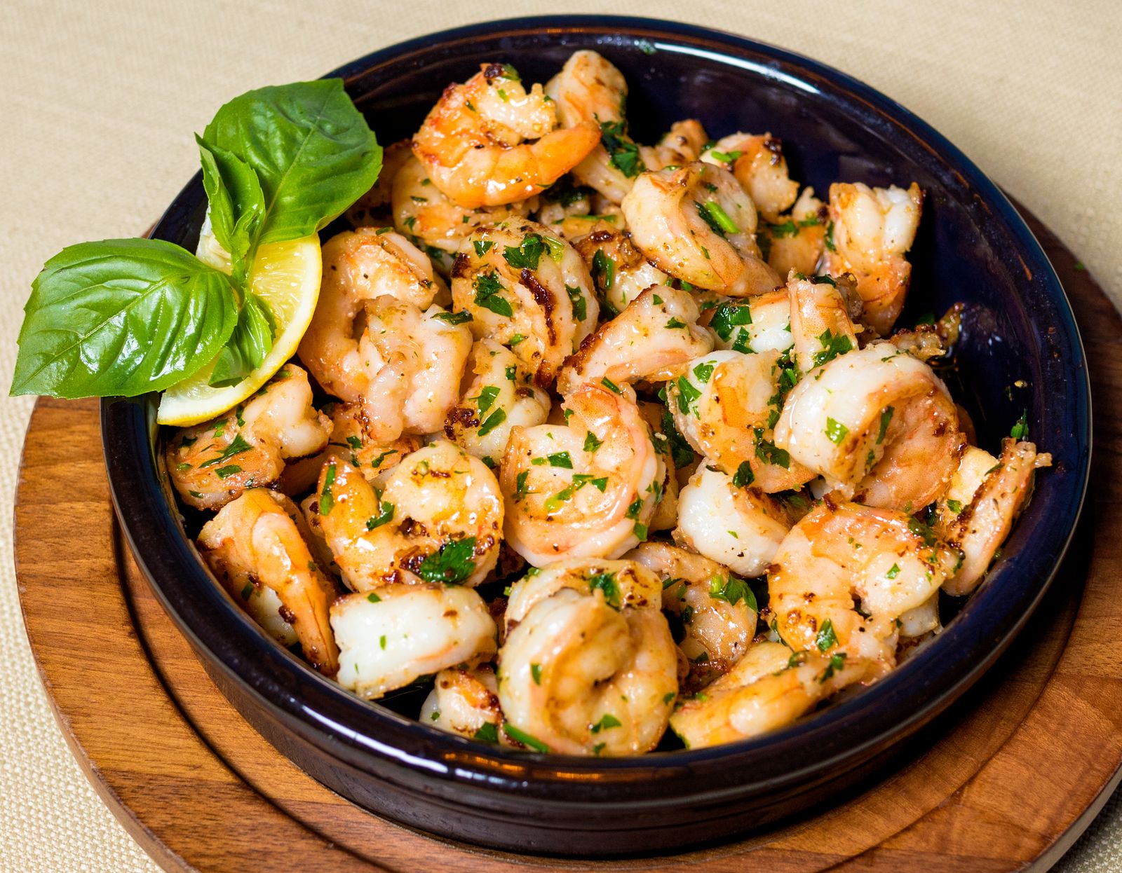 Garlic shrimp with herbs and lemon in a wooden bowl