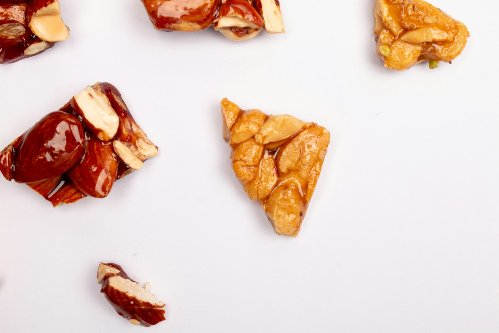 Pieces of peanut brittle scattered on a white surface
