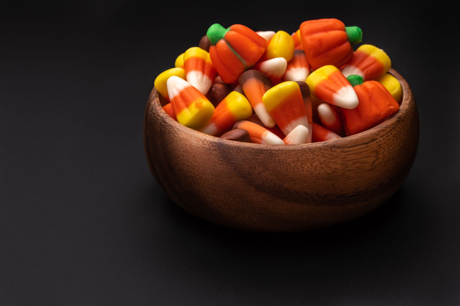 Bowl of tri-color candy corn on a dark background