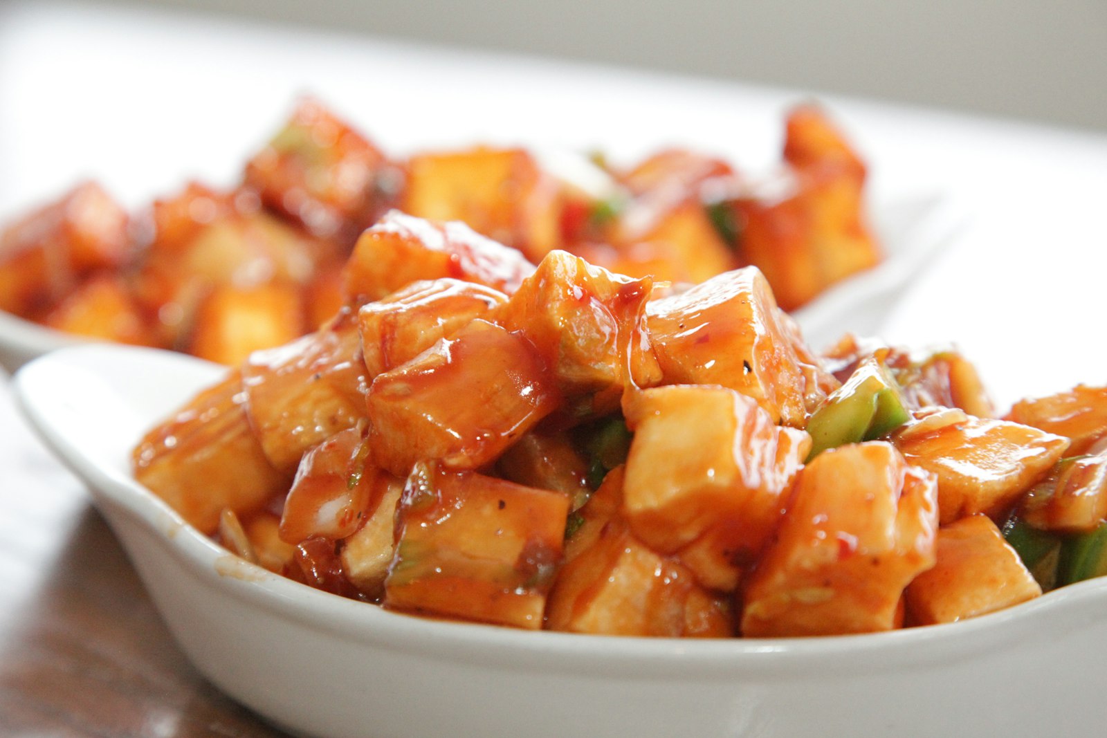 Bowl of golden paneer cubes in spiced sauce