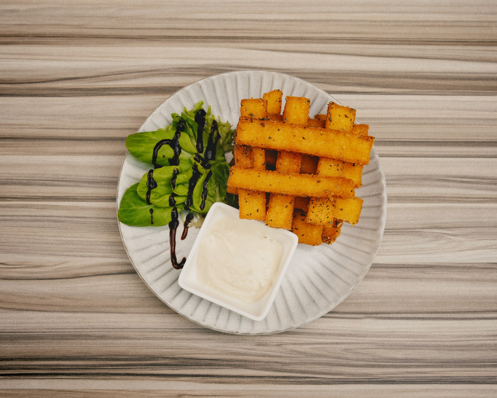 Golden fried sticks on a plate with a bowl of creamy dip, homemade fries