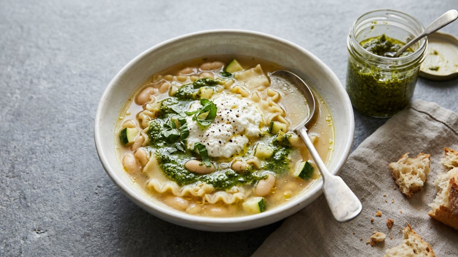 Pesto lasagna soup with white beans, zucchini and a swirl of basil pesto
