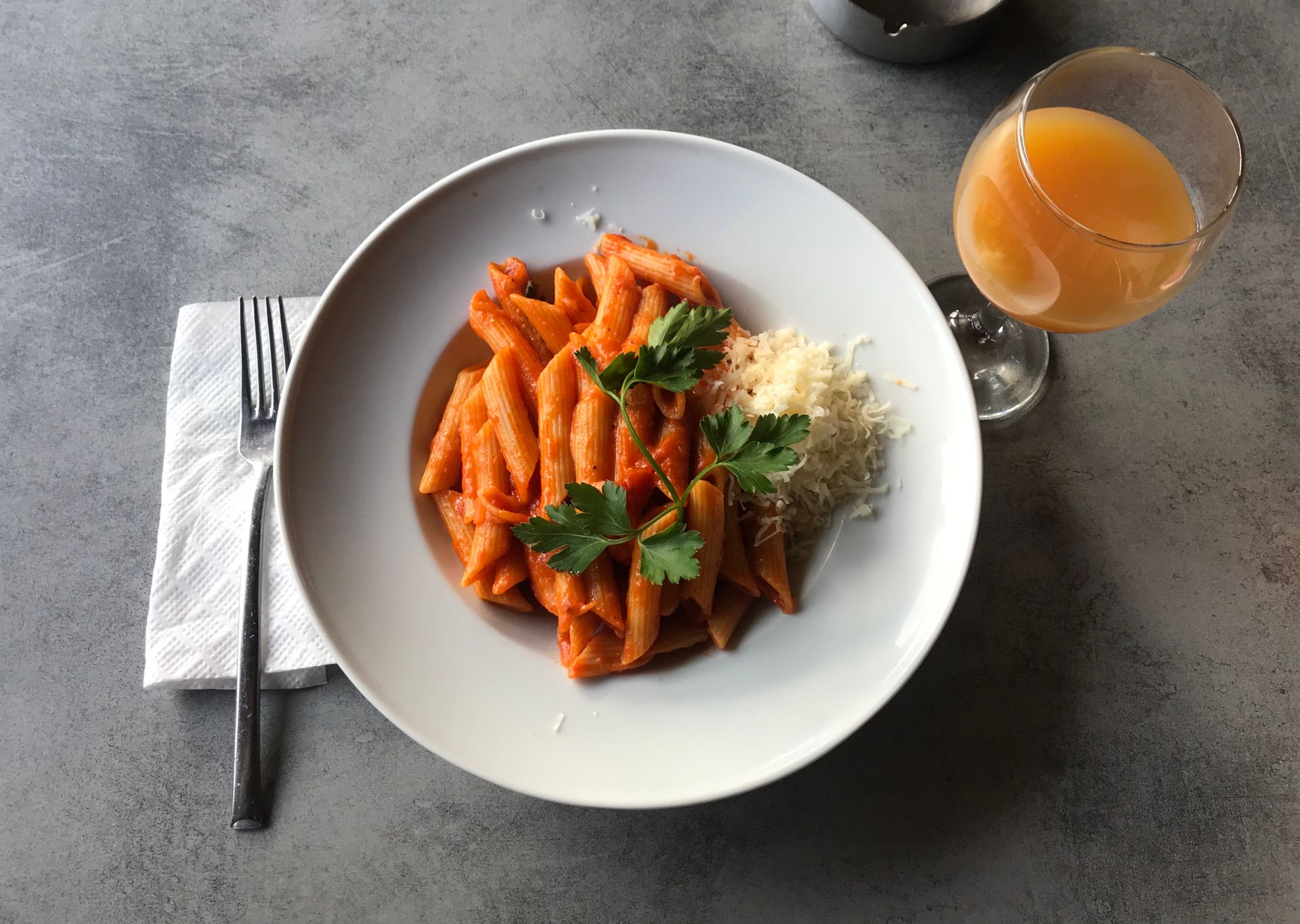 Penne in a pink tomato cream sauce with herbs on a white plate