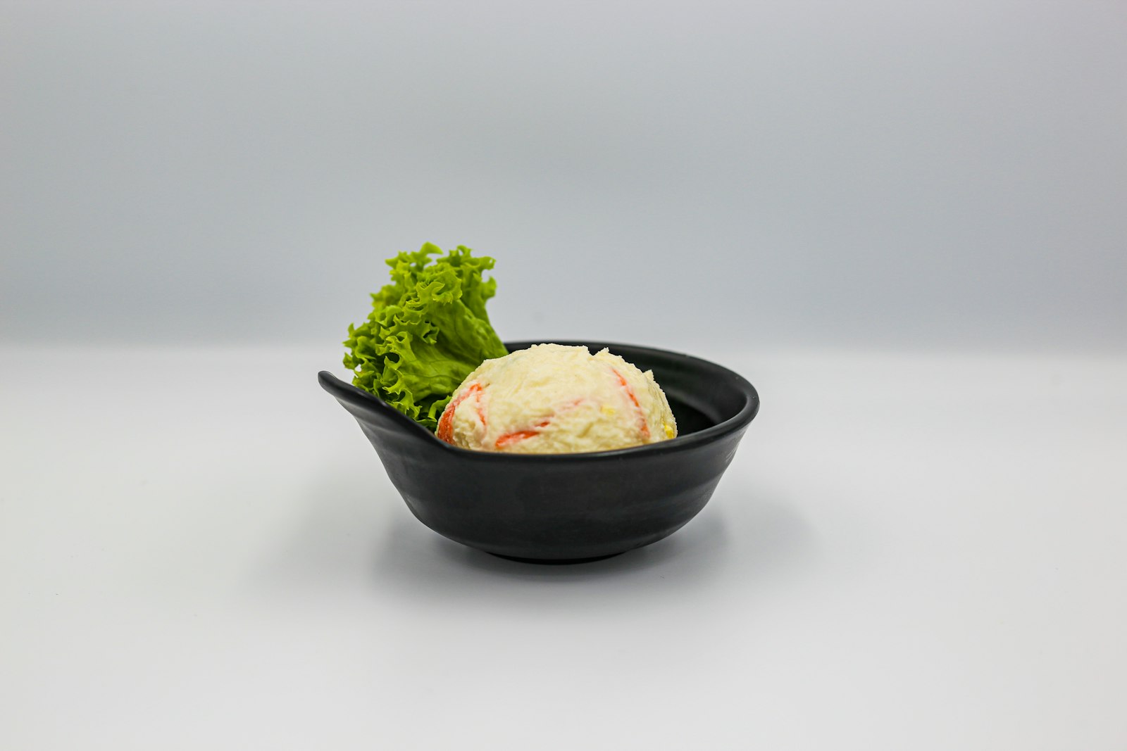 Small bowl with a creamy scoop topped with fresh greens