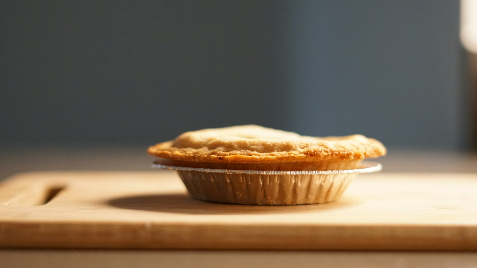A small golden pot pie on a wooden board