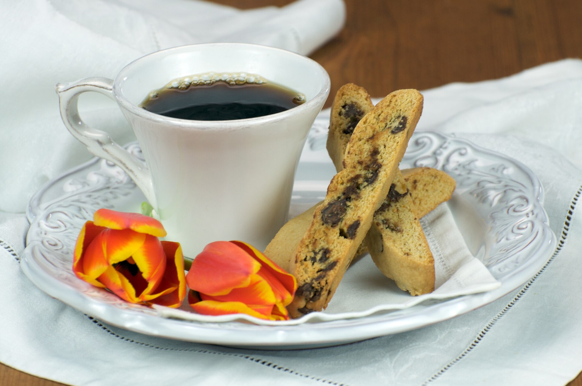 Coffee chocolate chip biscotti on a saucer next to a cup of coffee