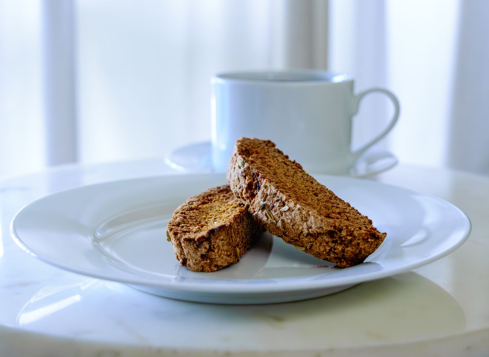 Biscotti: two vanilla bean slices on a plate with a coffee cup