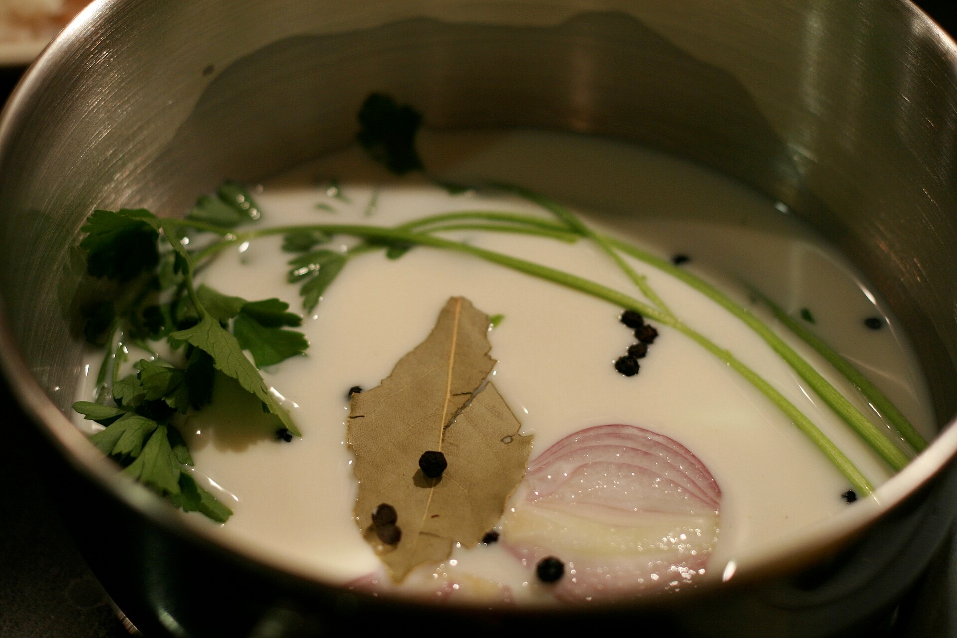 Milk infusing with bay leaf and onion for the creamed chipped beef white sauce