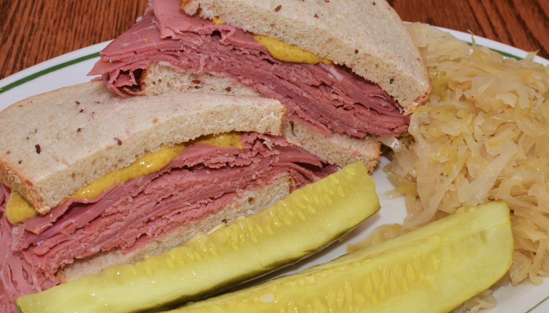 Corned beef sandwich on rye with a pickle and sauerkraut