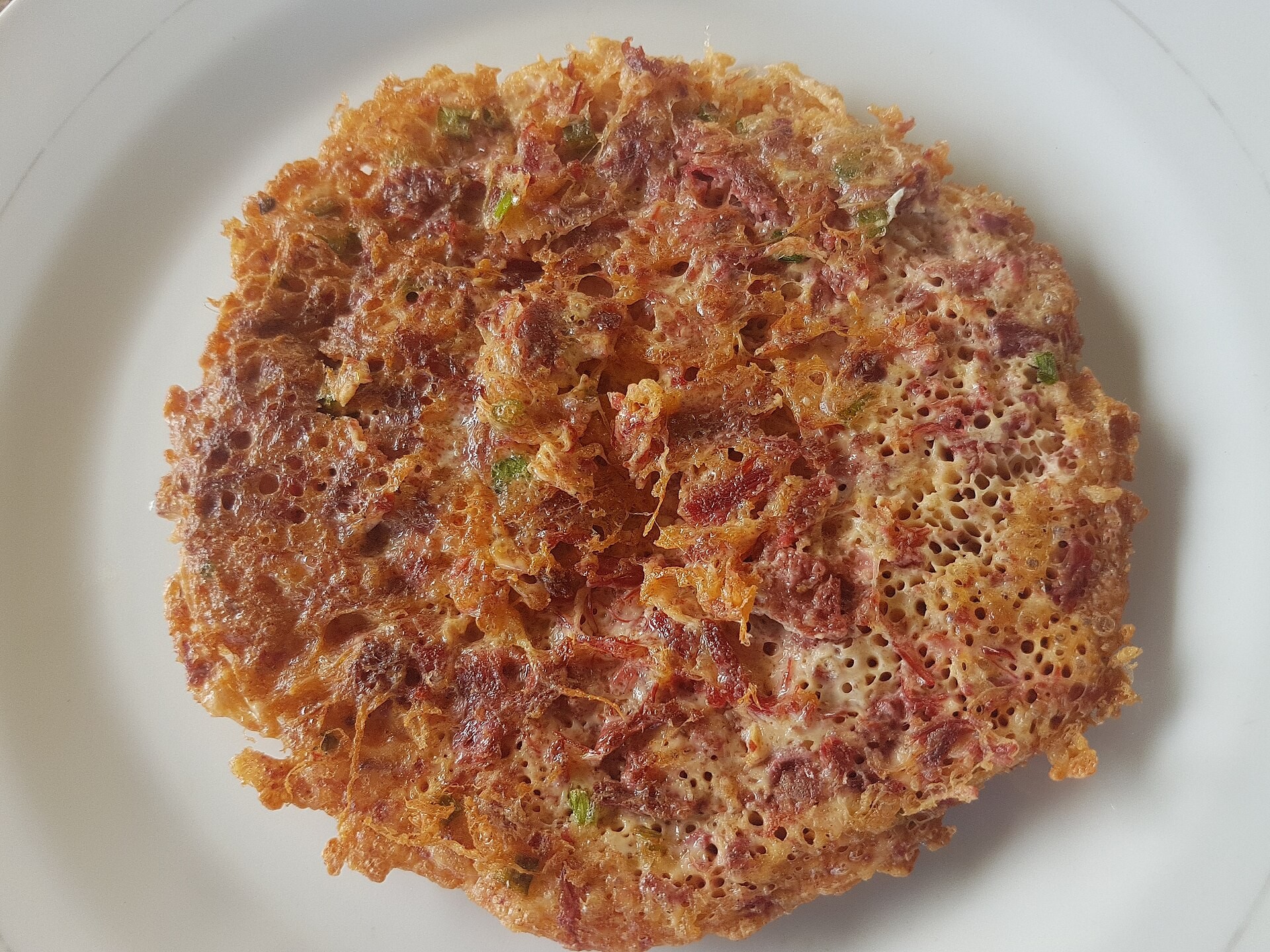 Crispy Filipino corned beef omelet patty on a white plate