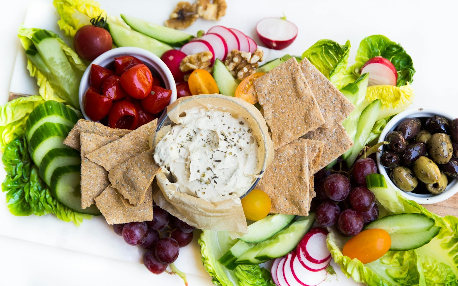 Raw vegetable platter with a creamy dip, crackers and olives