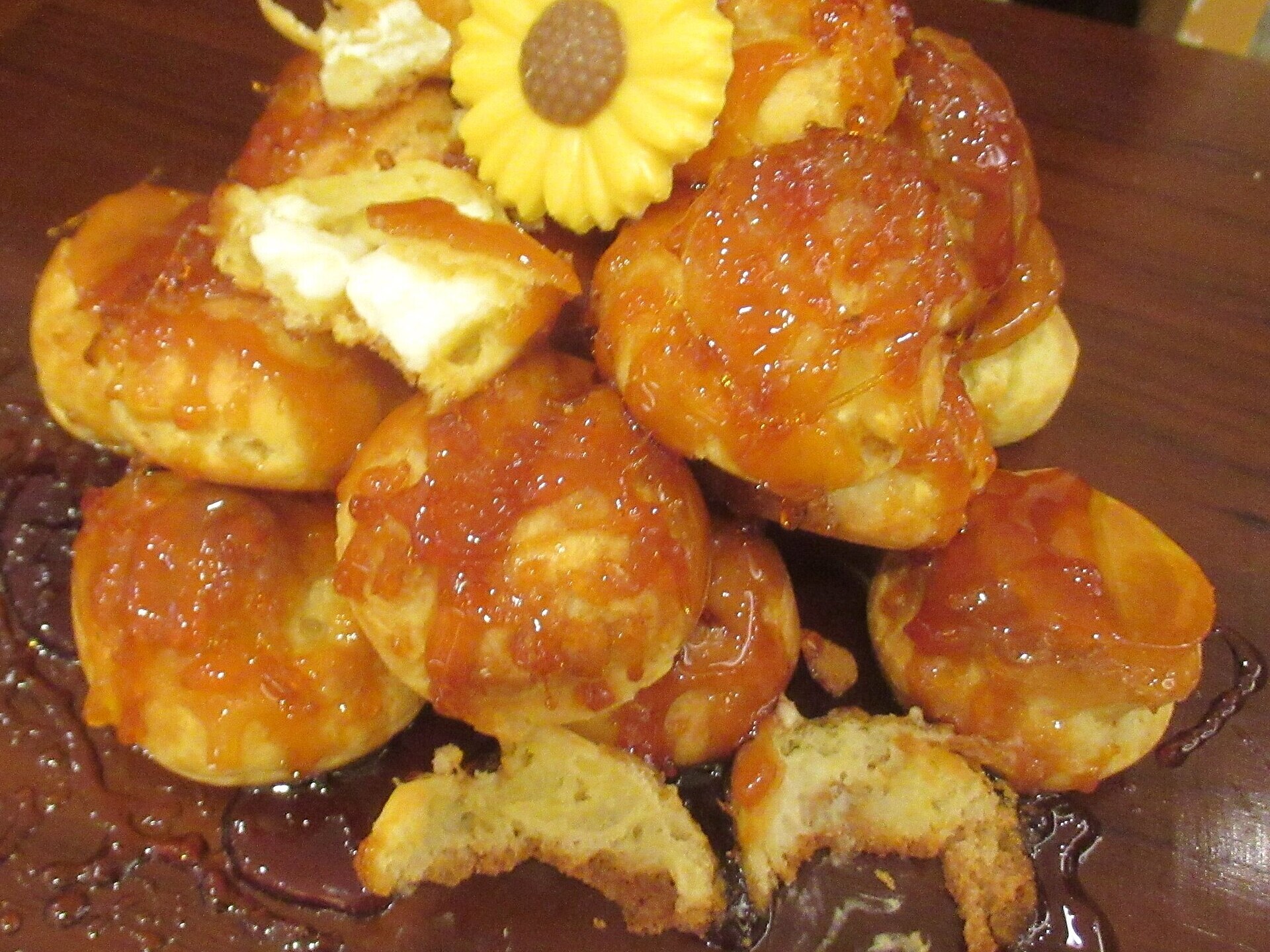 Cream puffs coated in golden caramel piled on a board