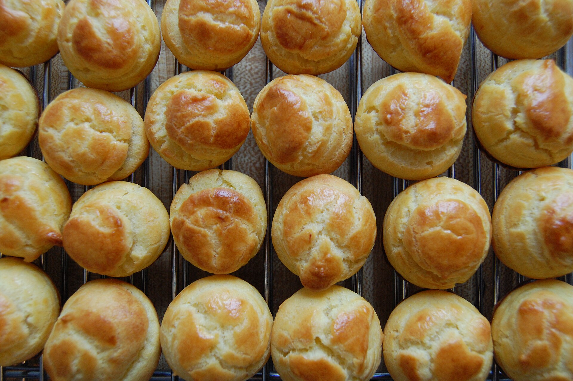 Cream puffs: baked golden choux buns cooling on a wire rack