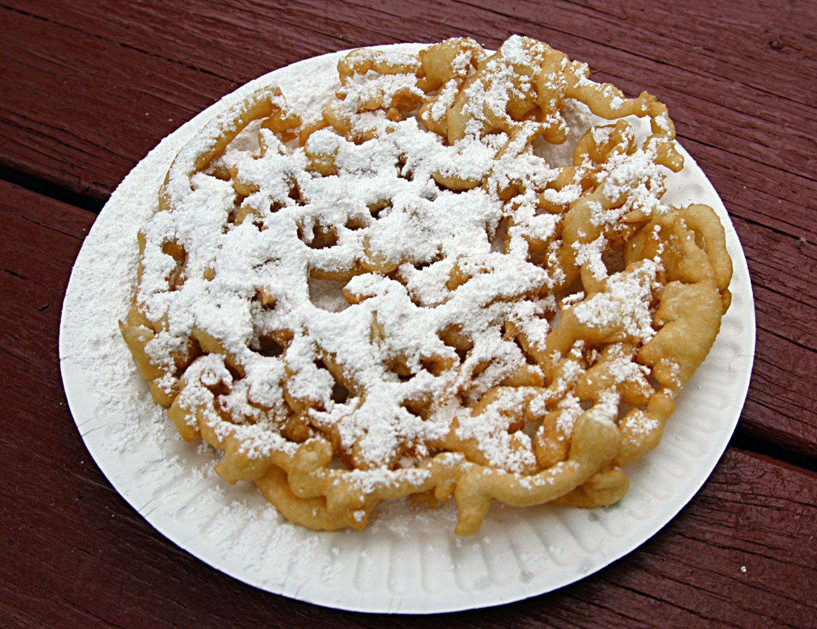 State fair foods classic: funnel cake dusted with powdered sugar on a paper plate