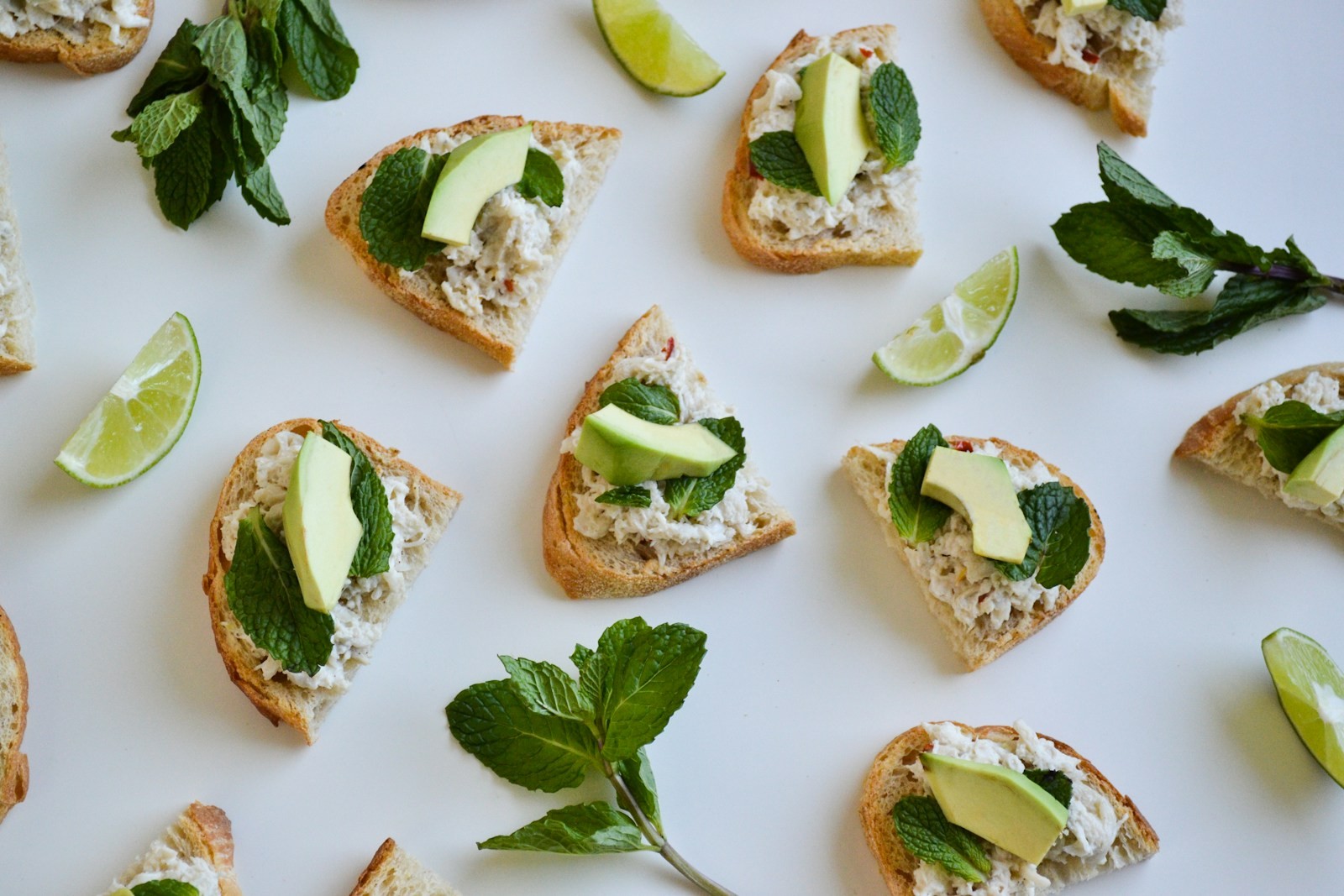 Avocado, mint and lime crostini on a white table