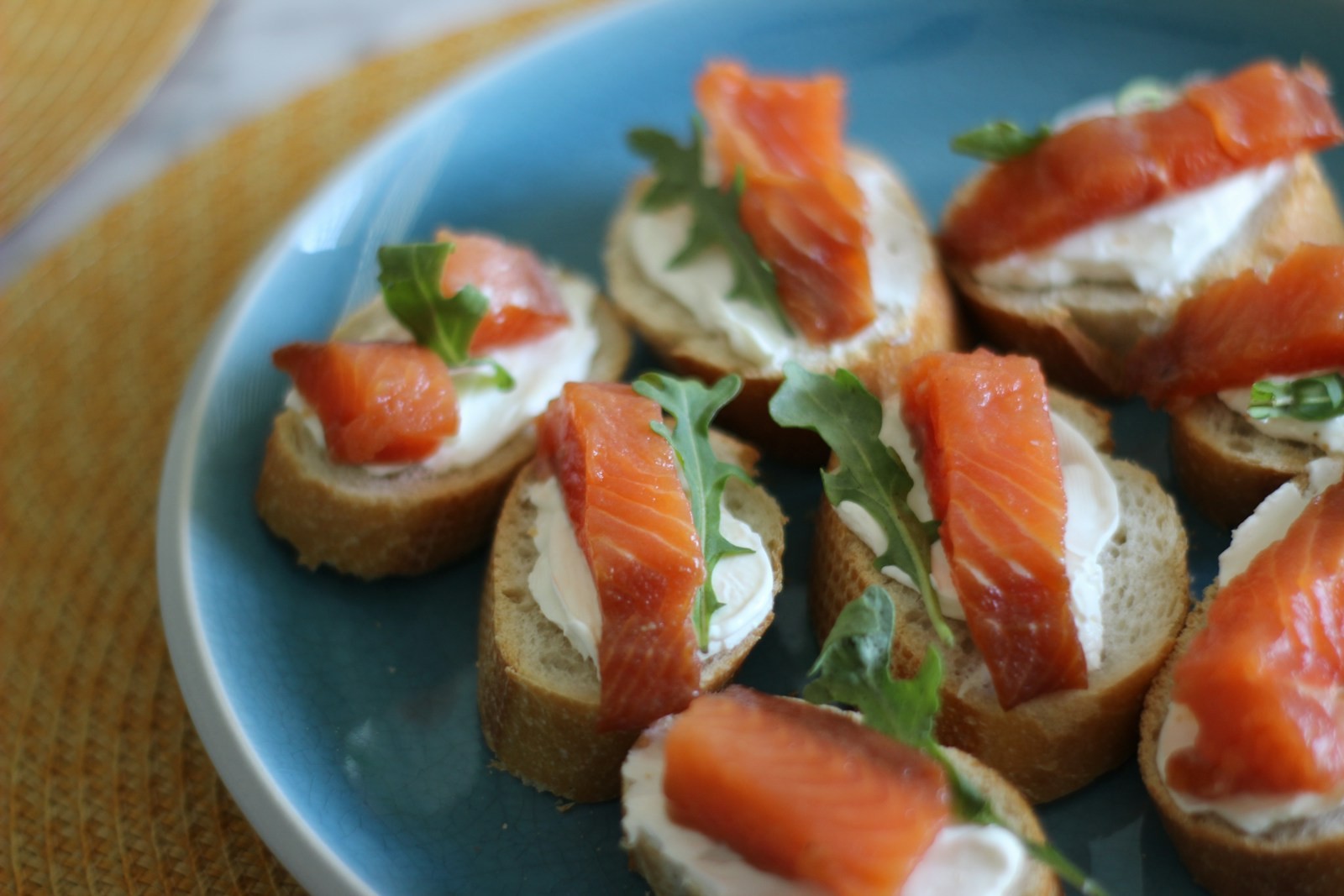 Smoked salmon crostini with cream cheese on a blue plate