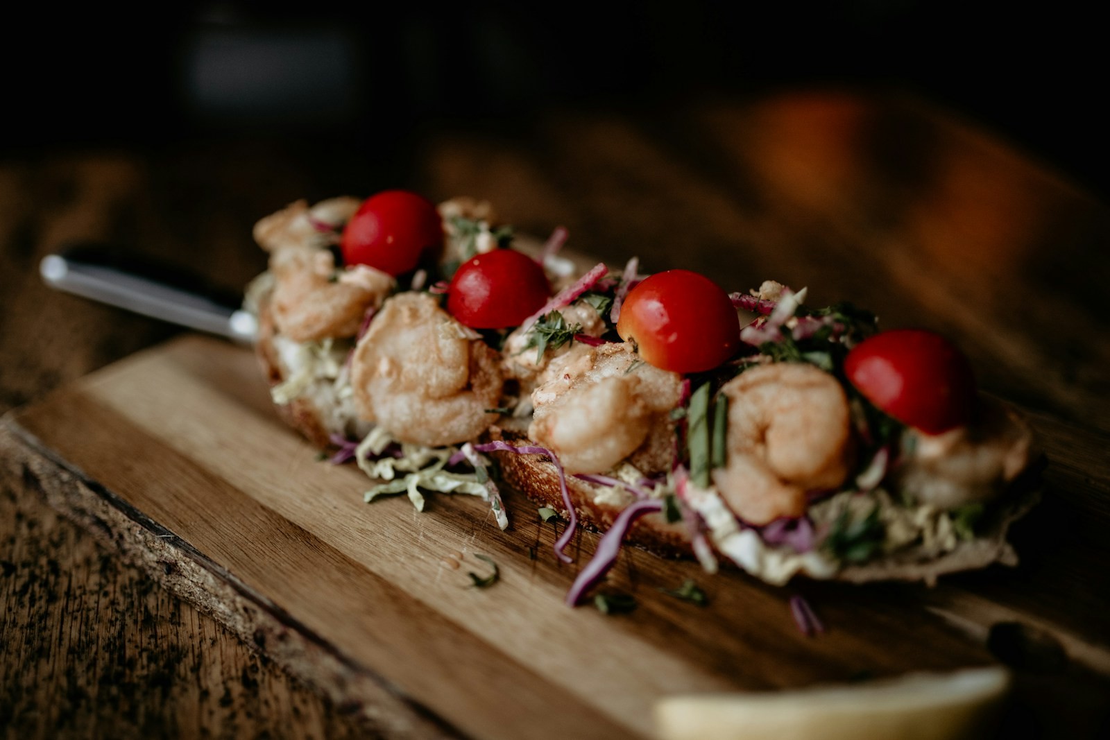 Shrimp crostini with cherry tomatoes on a wooden board
