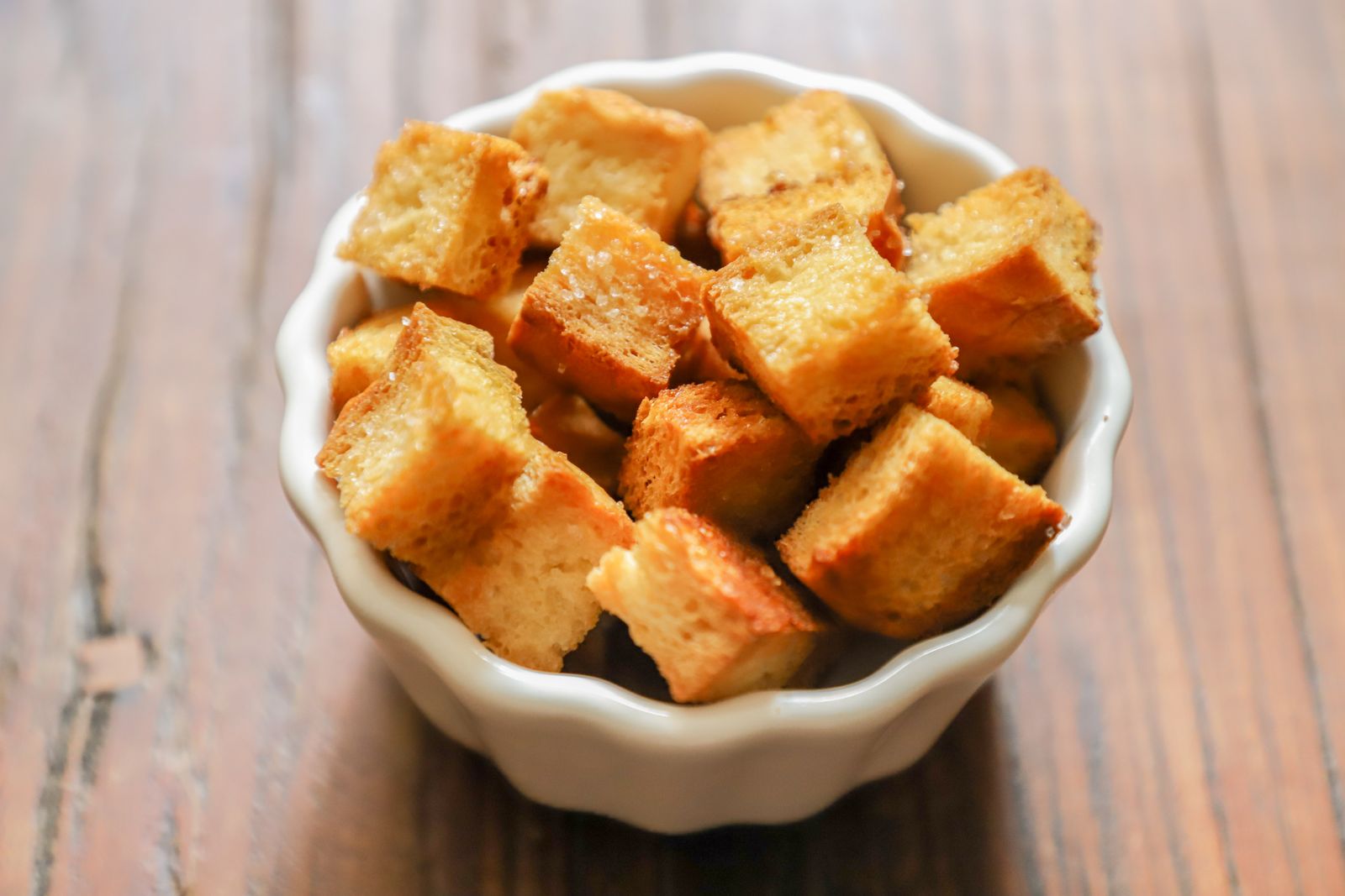 Golden homemade croutons in a white bowl