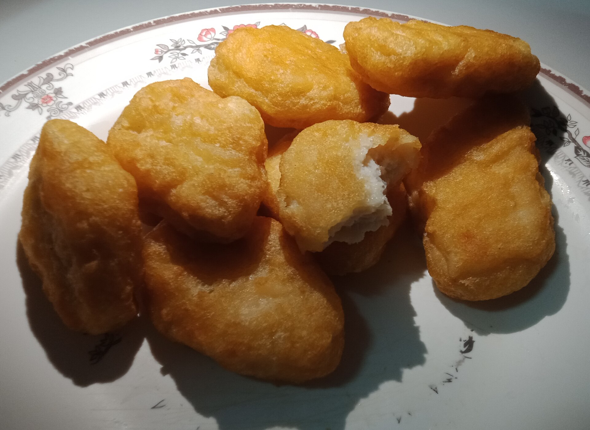Homemade chicken nuggets piled on a white plate