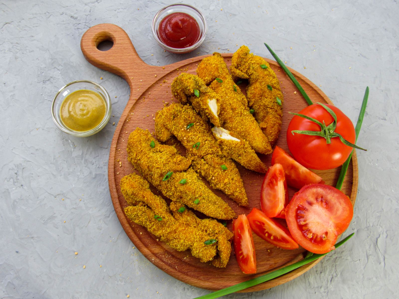 Herb-crusted tenders with tomatoes on a wooden board