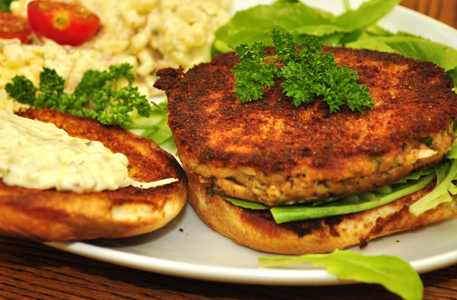 A crispy salmon patty on a bun with parsley