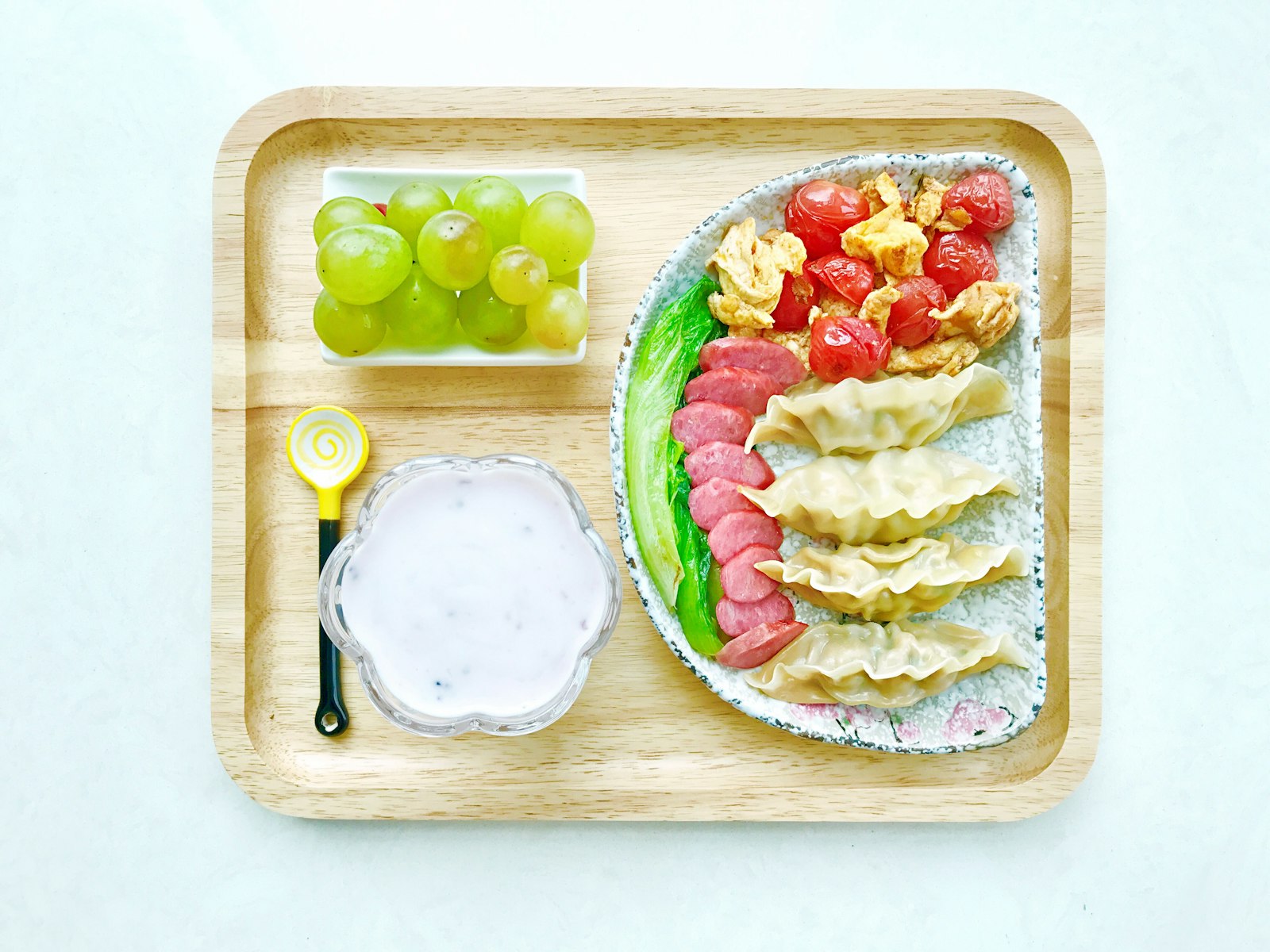 A divided lunch tray with fruit, vegetables and a sandwich