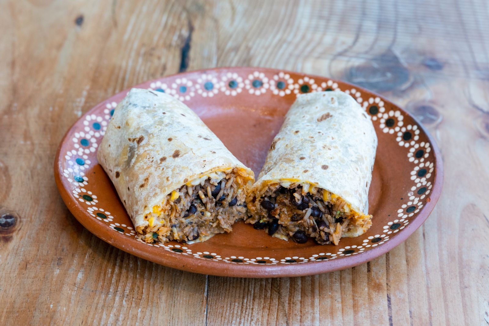 Bean and cheese burritos cut in half on a plate