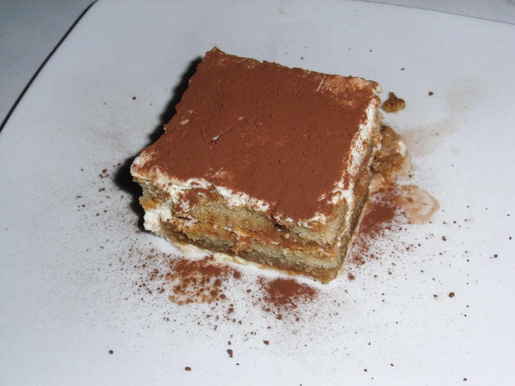 Slice of classic Italian tiramisu dusted with cocoa