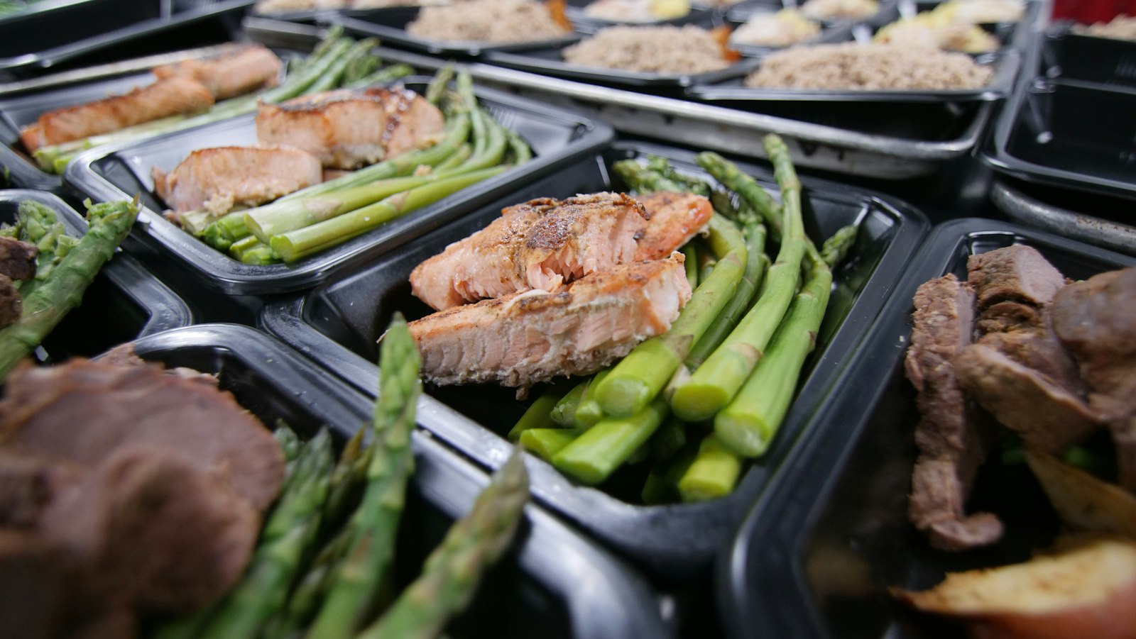 Meal prep containers with salmon, asparagus and greens