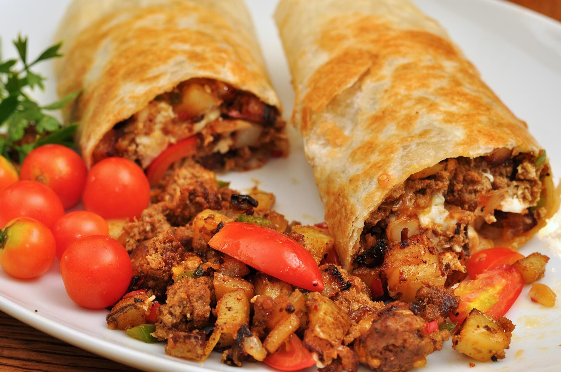 Two griddled breakfast burritos with potatoes and tomatoes