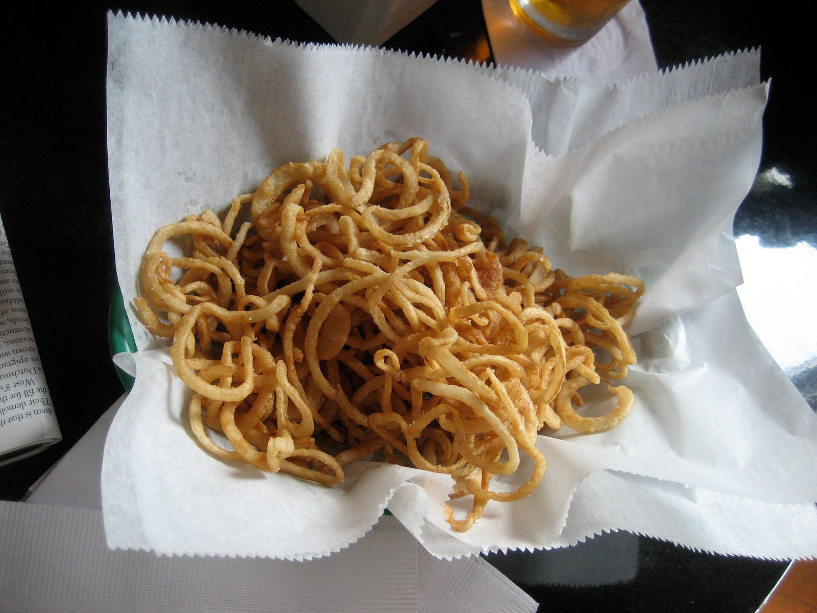 Thin crispy fried onion strings in a paper-lined basket