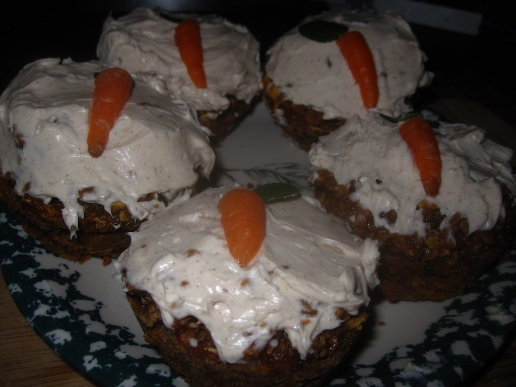 Cupcakes with cream cheese frosting topped with little orange frosting carrots