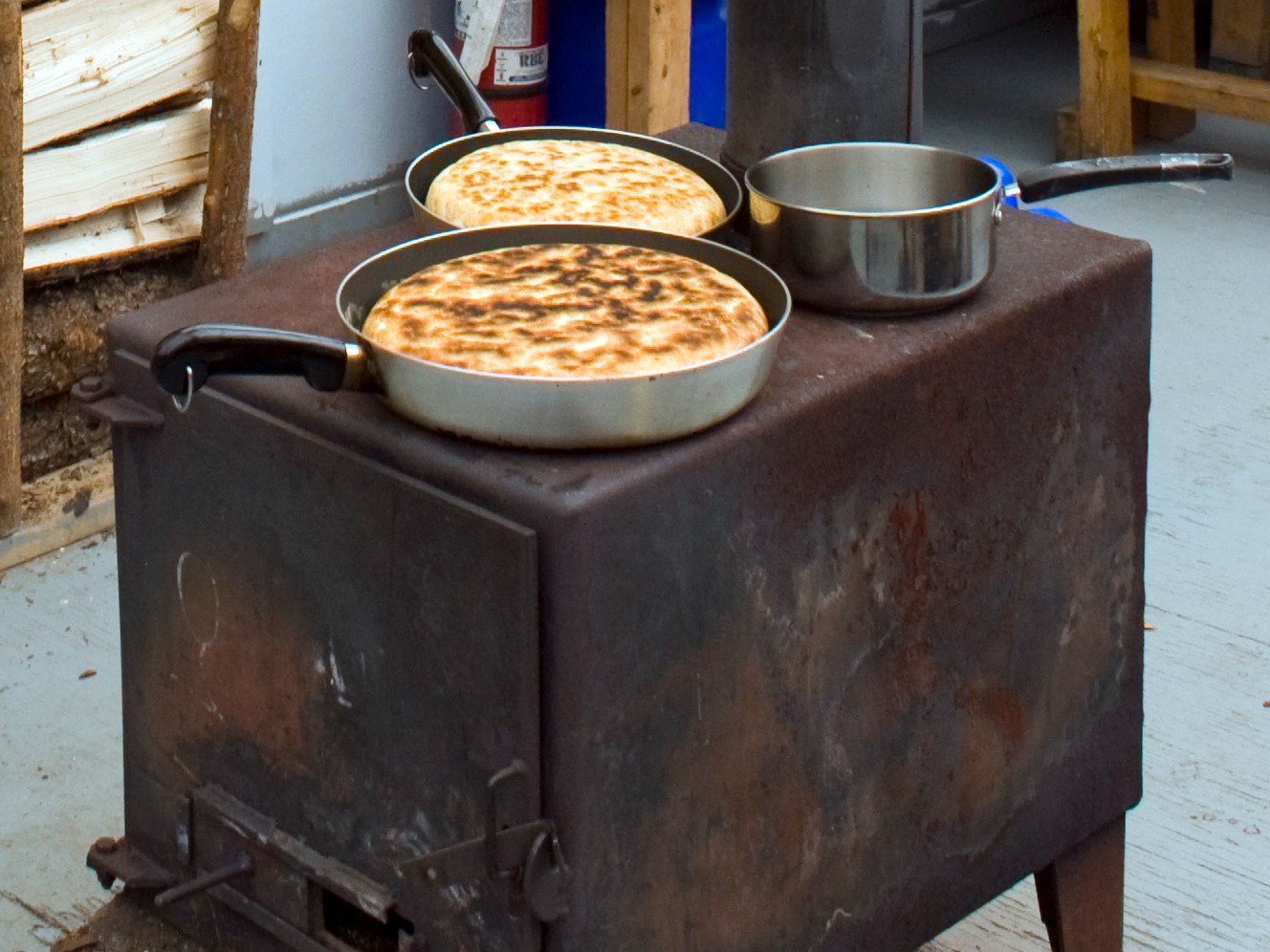 Pan of bannock cooking on a cast iron wood stove