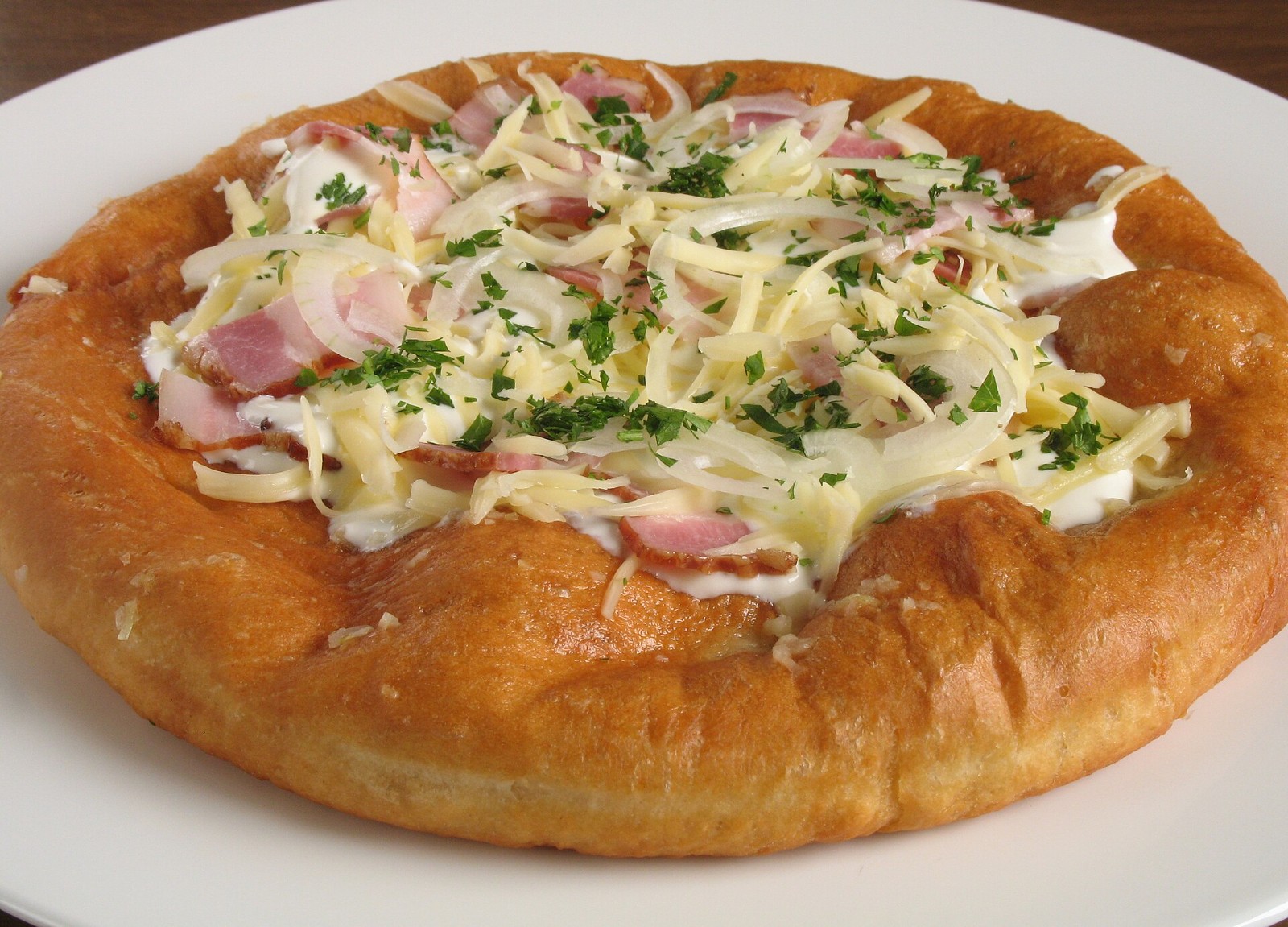 Hungarian langos topped with sour cream, cheese and ham