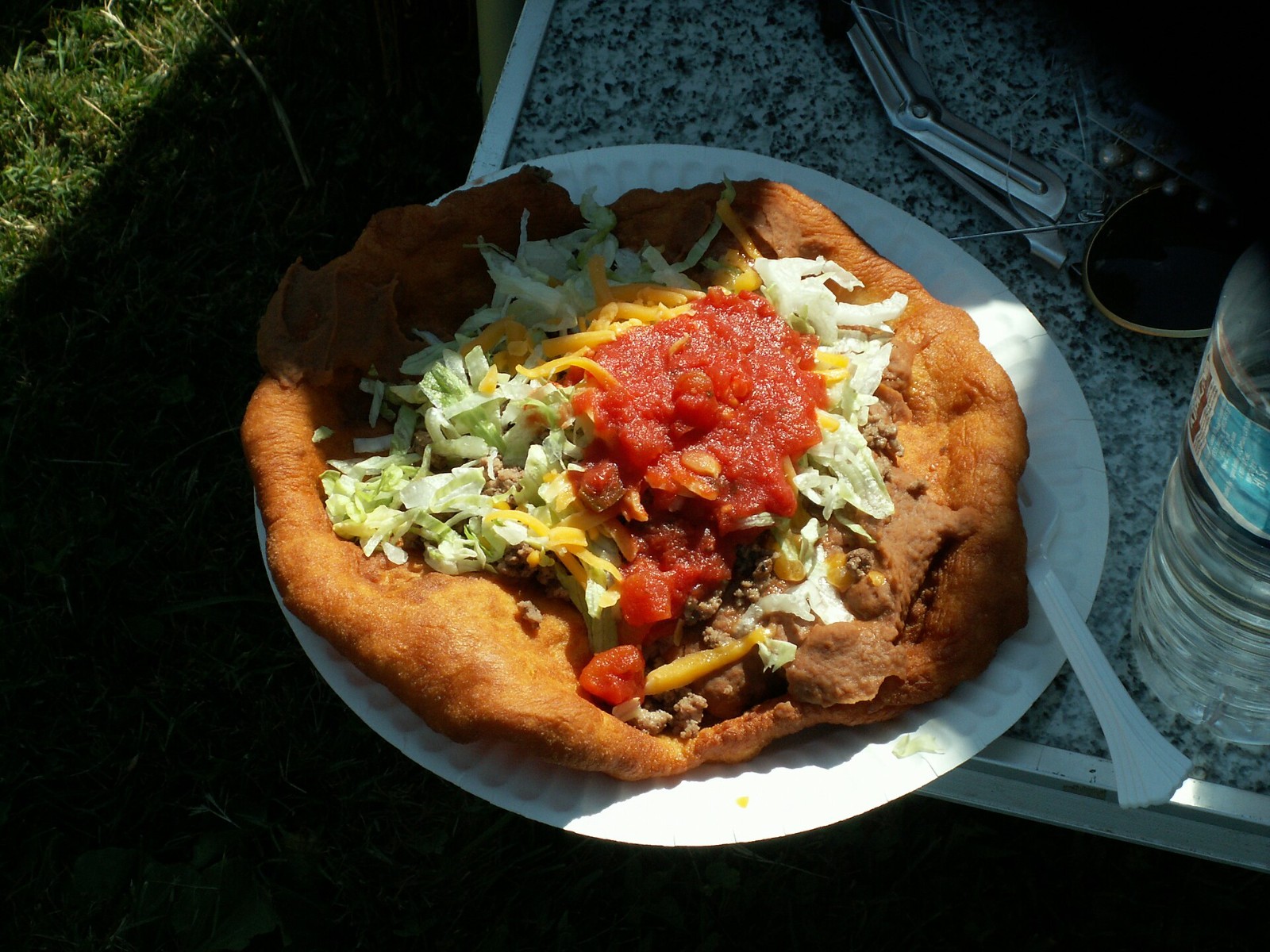 Navajo taco topped with salsa, lettuce and red chile