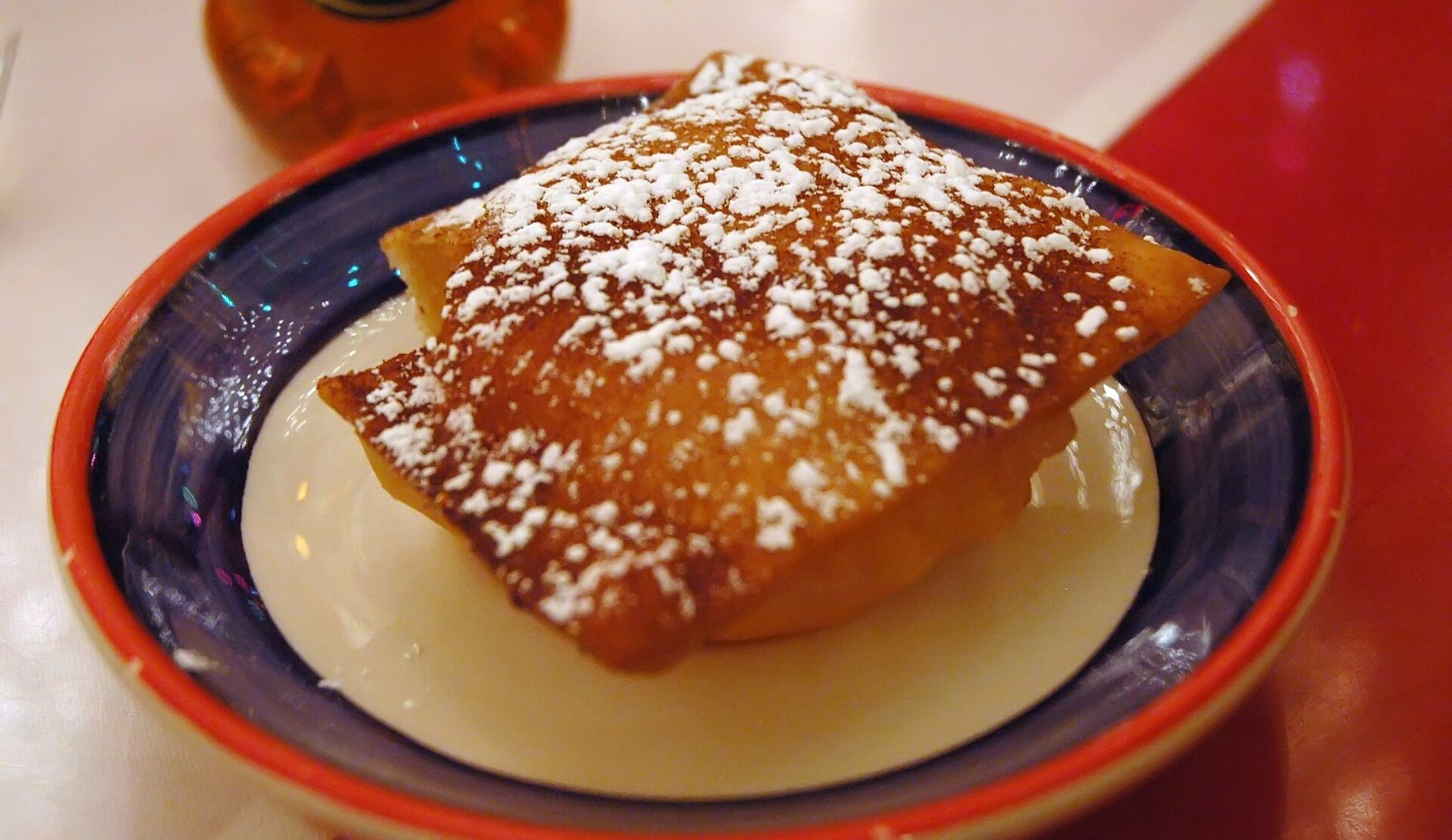 New Mexico sopaipilla dusted with sugar on a dark plate