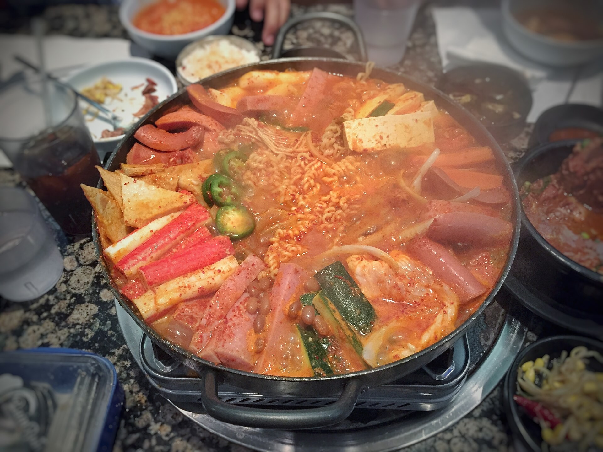 Korean army stew with sliced sausages, ham and kimchi in a wide pot