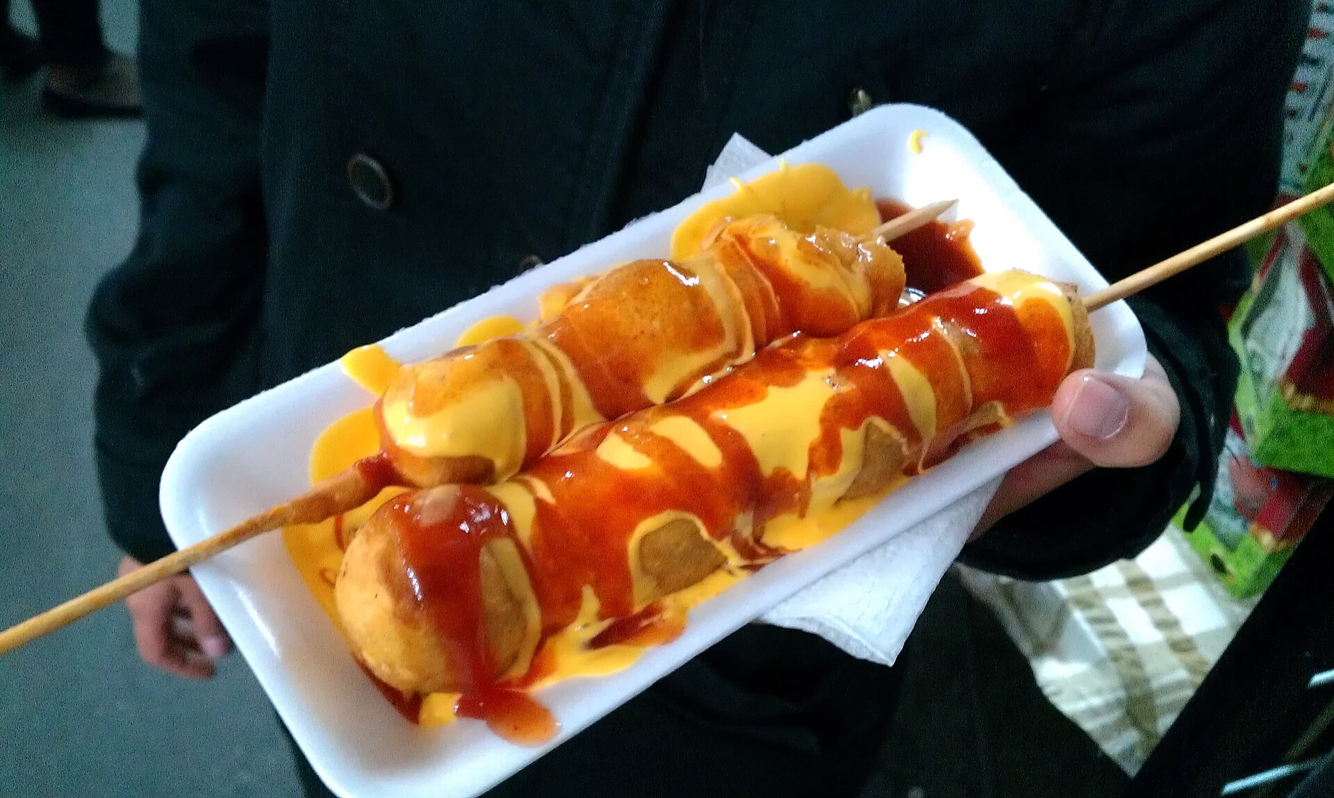 Corn dogs drizzled with ketchup and mustard on a tray