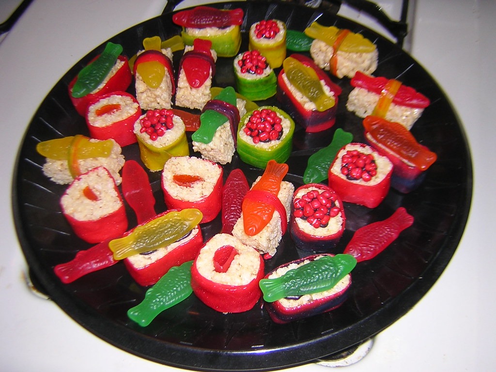 Food illusion candy sushi rolls made with crispy rice treats and gummy fish on a black platter