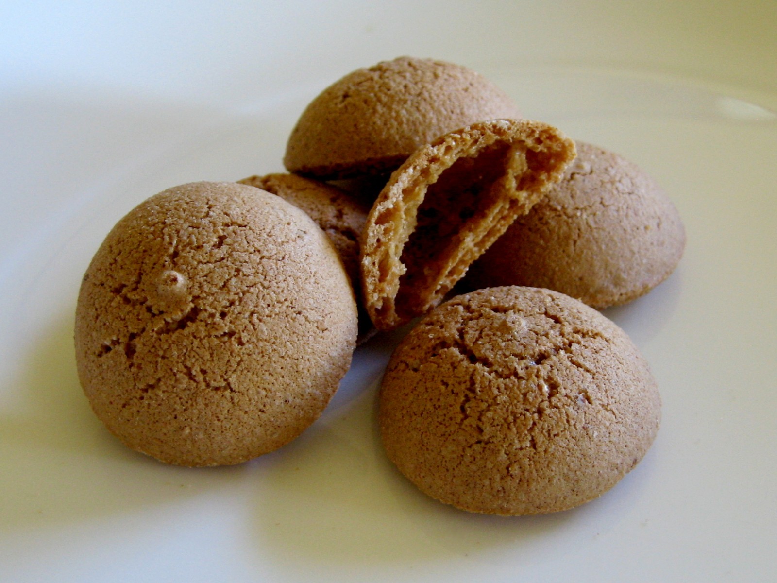 Crackled round amaretti with one broken open to show the crumb