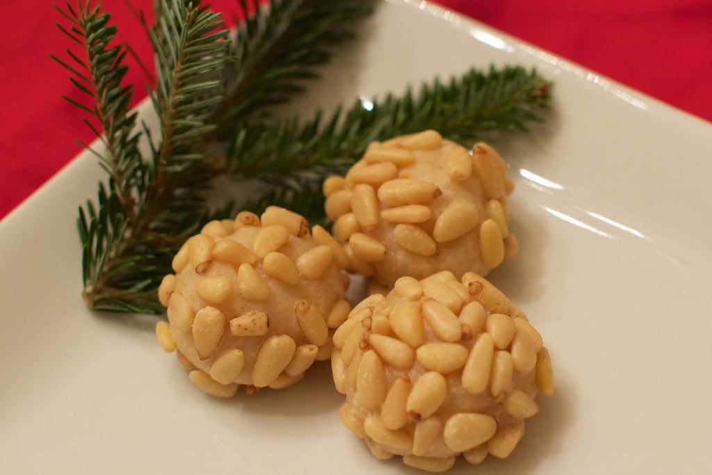 Pine nut covered pignoli on a white plate with a fresh pine sprig