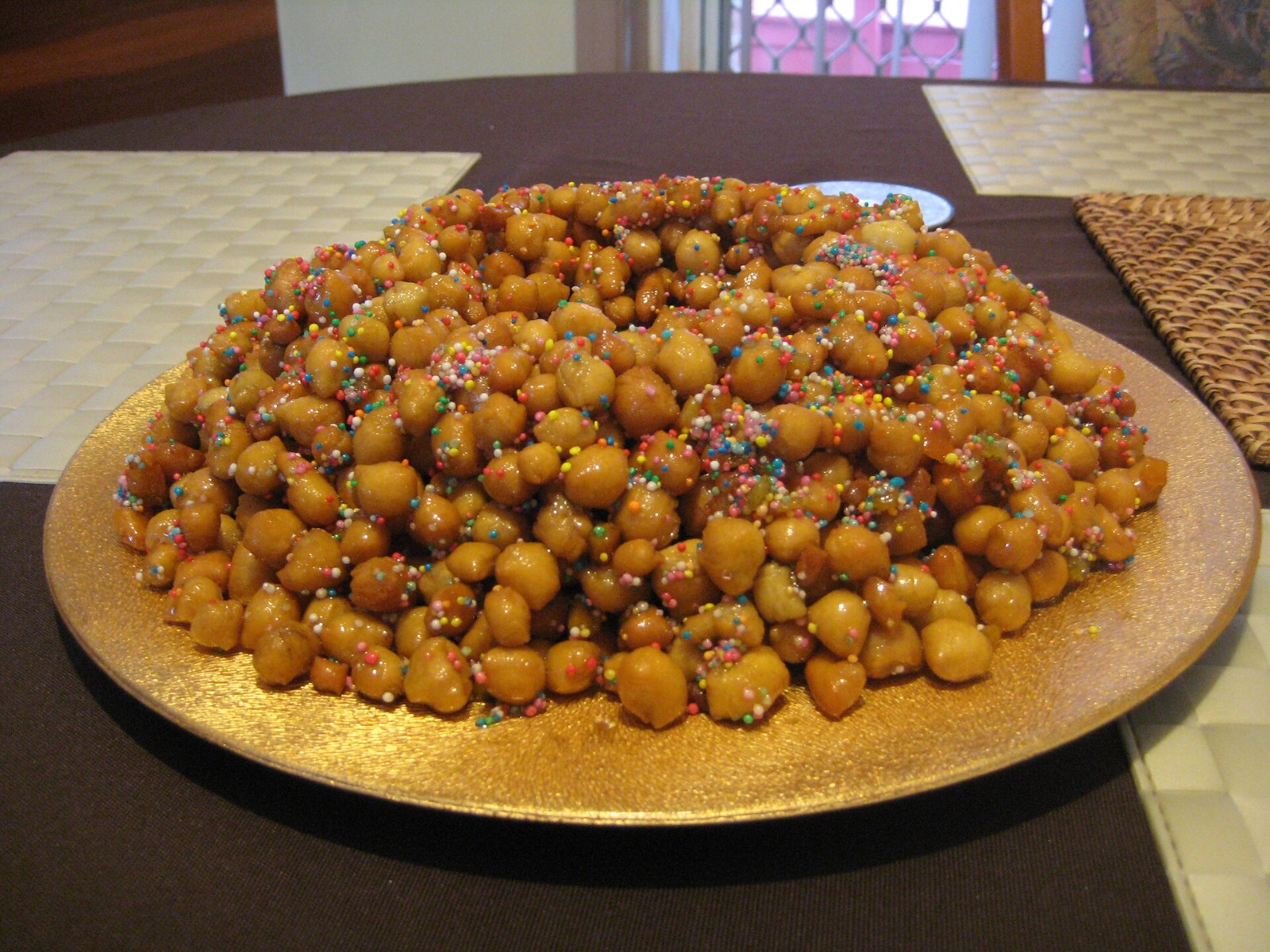 Honey glazed struffoli piled high on a golden plate